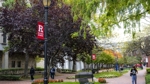 Students stroll through pedestrian walkway on the Rutgers Law School campus surrounded by rich foliage.