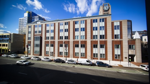 The exterior of a law school building under a bright blue sky.
