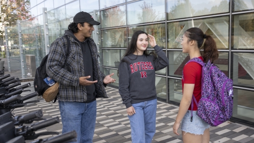 Three students meet outside a Rutgers building on a summer day.