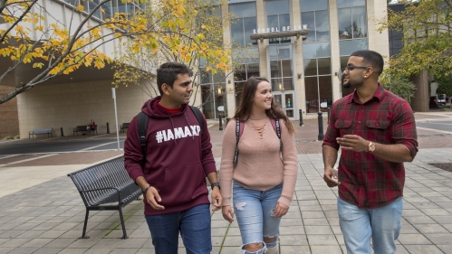 Three students talk while walking outdoors at Rutgers Law School.