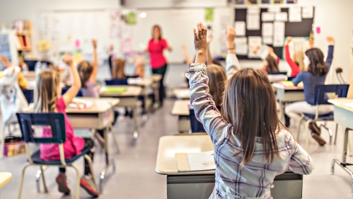 kids in classroom with hands raised