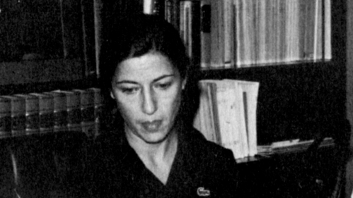 Black and white photo of a woman with a bookshelf behind her