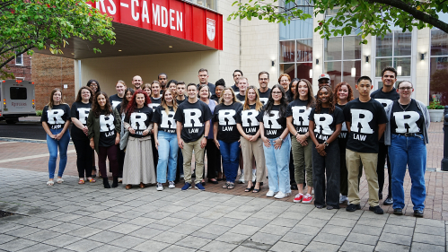 large group of people wearing black R Law tshirts standing on sidewalk outdoors
