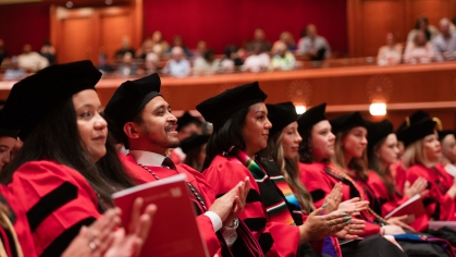 people seated next to each other in red graduation robes and black caps