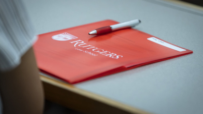 red Rutgers Law School folder with pen on a desk