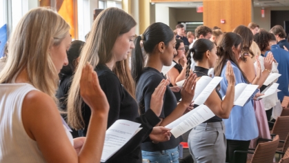 women students raising hands and reading from papers