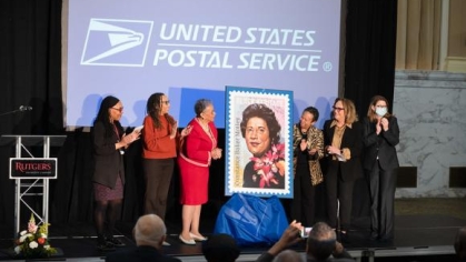 group of women standing on a stage with a giant postal stamp
