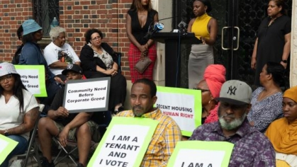 people holding signs in front of a speaker
