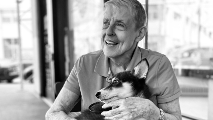 black and white photo of woman sitting down holding husky