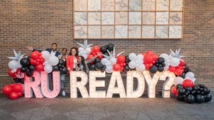 people posing for a photograph in front of balloons and a sign