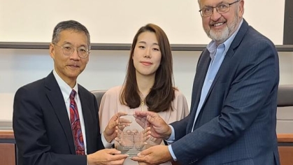 Three people holding an award and posing for a photograph