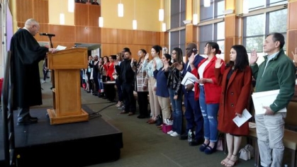 people standing and taking an oath from a person behind a podium