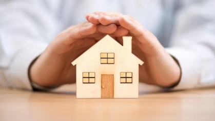 a miniature house covered by hands