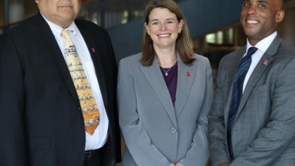 three people in suits posing for a photograph