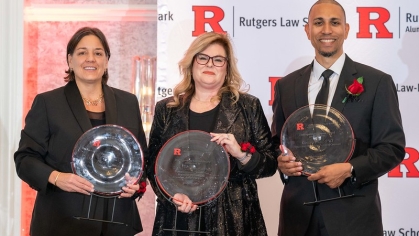 two women and one man holding awards