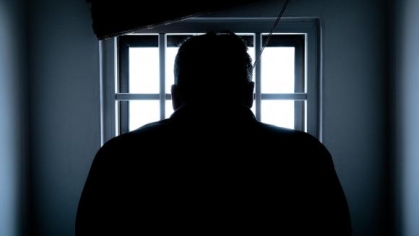 man looking out a window with bars