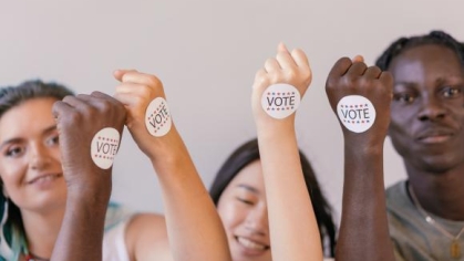 group of people raising their hands with a "vote symbol"