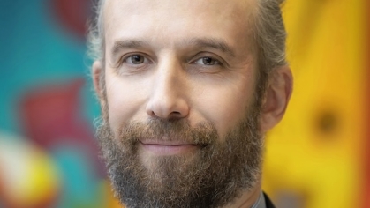man in suit smiling in front of colorful mural