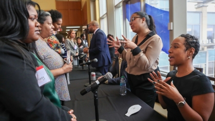 Group of people on both sides of black draped table speaking to each other