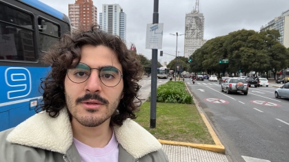 man wearing glasses posing in busy traffic intersection