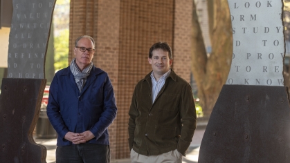 two men wearing jackets standing next to each other outside 