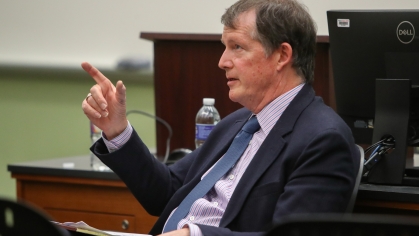 man in suit seated and pointing in classroom