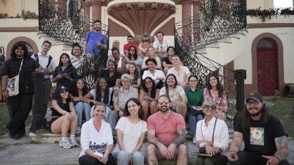 group of people seated on front building stairs and smiling