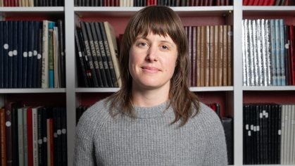 Woman grinning in front of bookcase