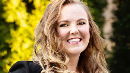 woman in black blazer and white shirt smiling outdoors