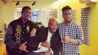 one man seated flanked by his two sons standing