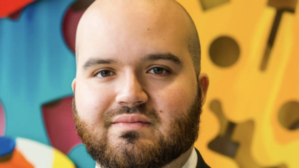 man in business suit looking forward in front of colorful artwork