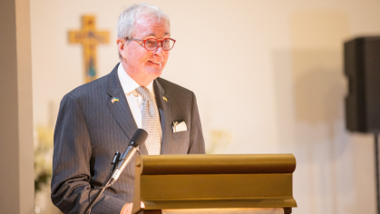 tall man wearing glasses standing at lectern