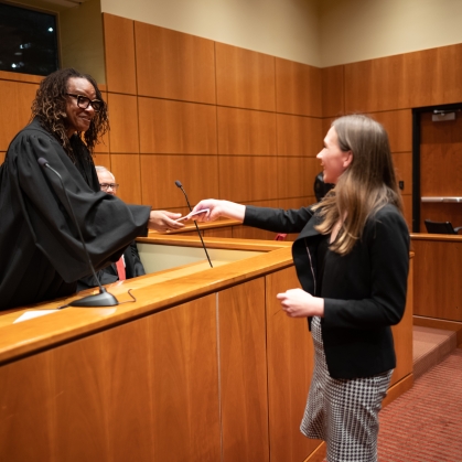 Judge shaking student’s hand from bench