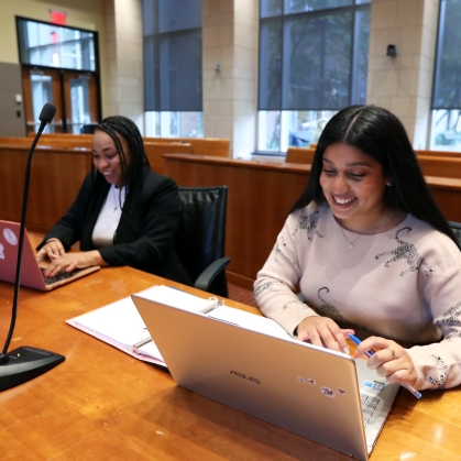 student women looking at laptops at counsel table in mock court