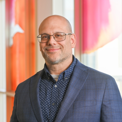 a bald man with a beard and glasses smiling
