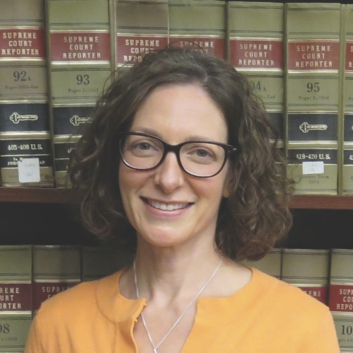 woman smiling in front of book shelf