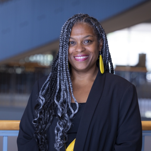 woman in black blazer and gray braids smiling