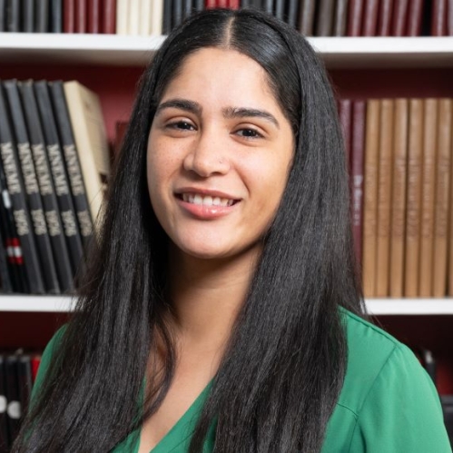 woman with long hair smiling in front of bookcase