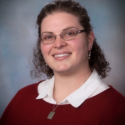 Woman smiling with glasses wearing red sweater and white collared shirt