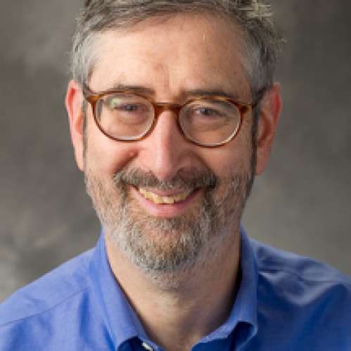 Man smiling wearing glasses and a blue button down shirt
