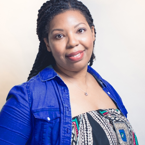 Woman grinning wearing multi-colored shirt and blue jacket