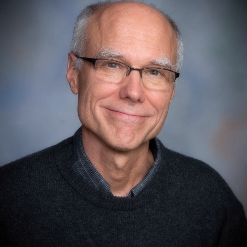 Man grinning with glasses wearing a black sweater