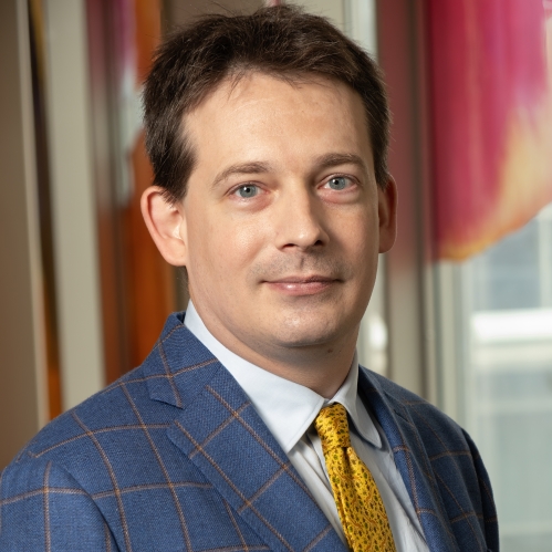Man grinning with yellow tie and blue suit with yellow stripes