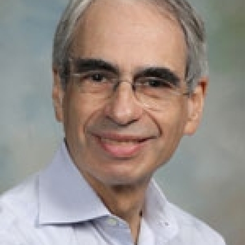 Man smiling with glasses wearing a blue button down shirt