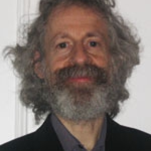Man grinning wearing grey shirt and black suit jacket