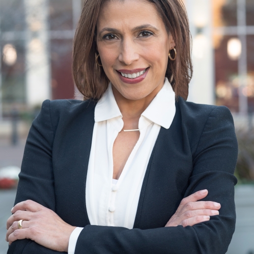 Woman smiling with white collared shirt, black suit jacket, with crossed arms