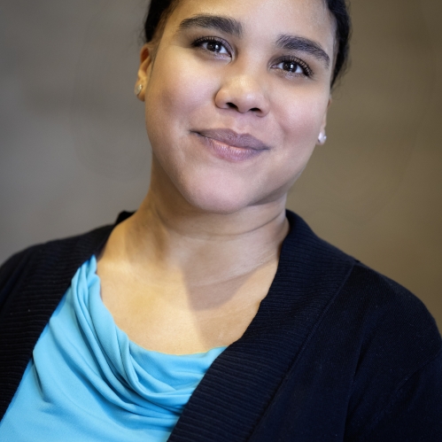 woman in black blazer and blue shirt grinning
