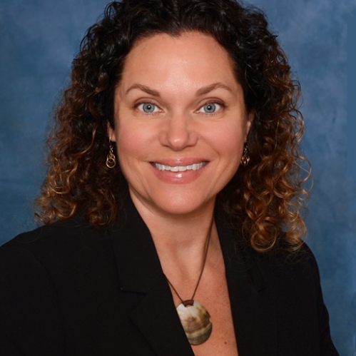 headshot of woman smiling in front of blue backdrop