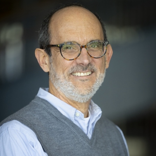 man with gray sweater and blue shirt wearing glasses