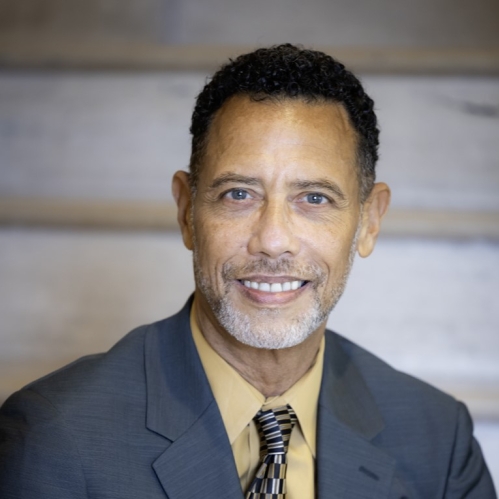 Man in blue suit smiling and sitting on stairs